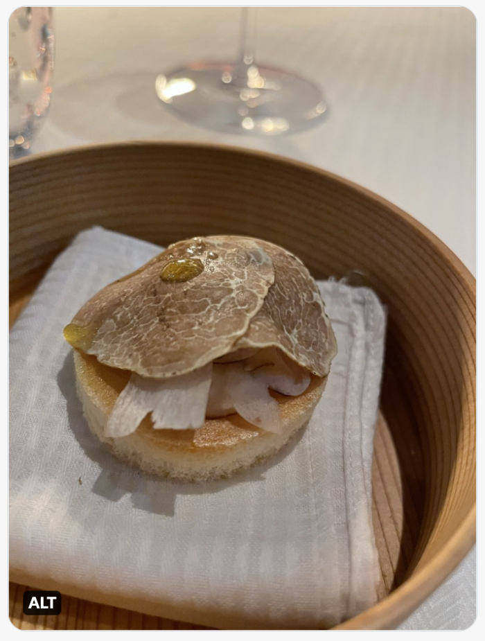 Shaved truffle over visible shavings of cheese, on a round meringue